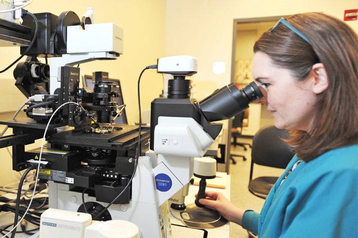 Researcher looking through a microscope.