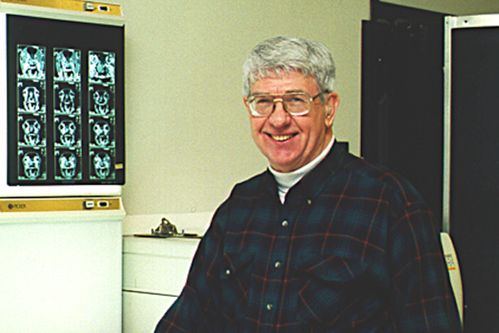 Dr. Jack Alexander standing with radiographs to his right.
