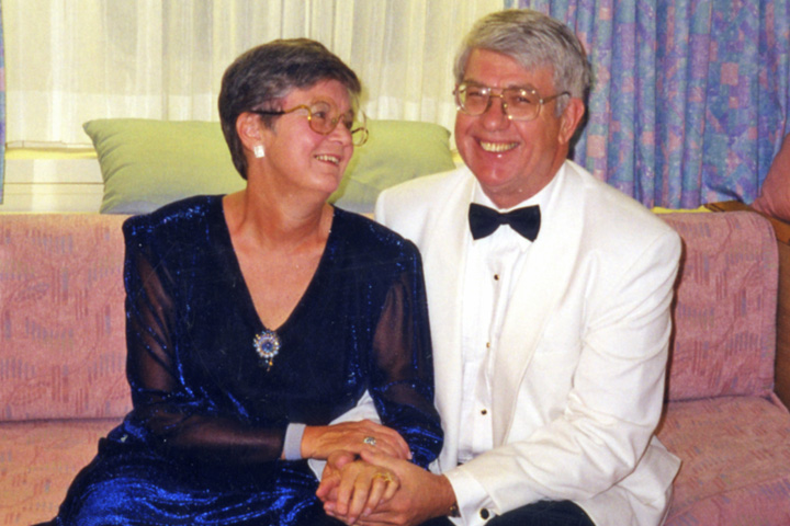 Marilyn and Jack dressed in formal attire. He is in a white tux with a black bow tie, and she has a navy blue dress on.
