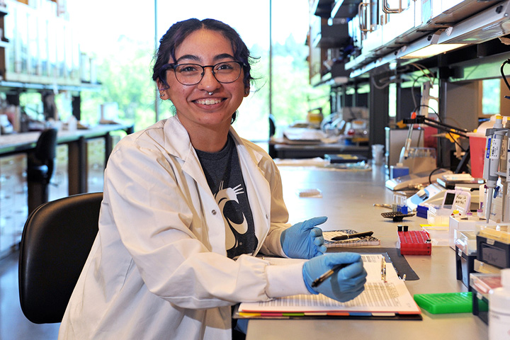 Alexandra, in a lab coat, recording data.