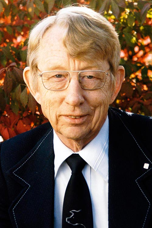 Dr. Leo Bustad outside the college with a autumn leaves as the backdrop.