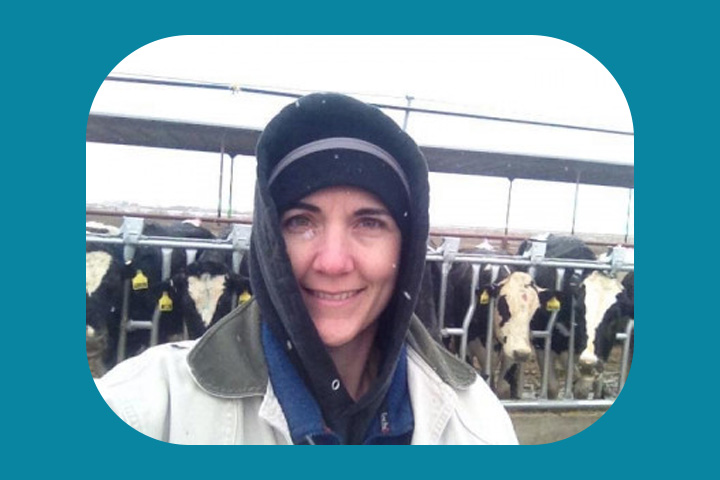 Elizabeth Quesnell Khotz bundled up in the winter with dairy cows behind her.