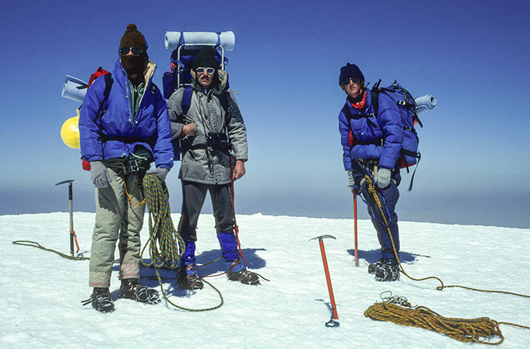 The three hikers at the summit. The sky is blue.