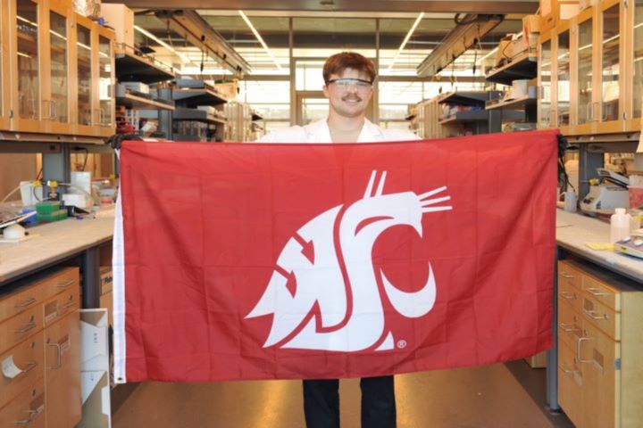Neuroscience student Peter Yunker holds a WSU flag in a research lab on campus.