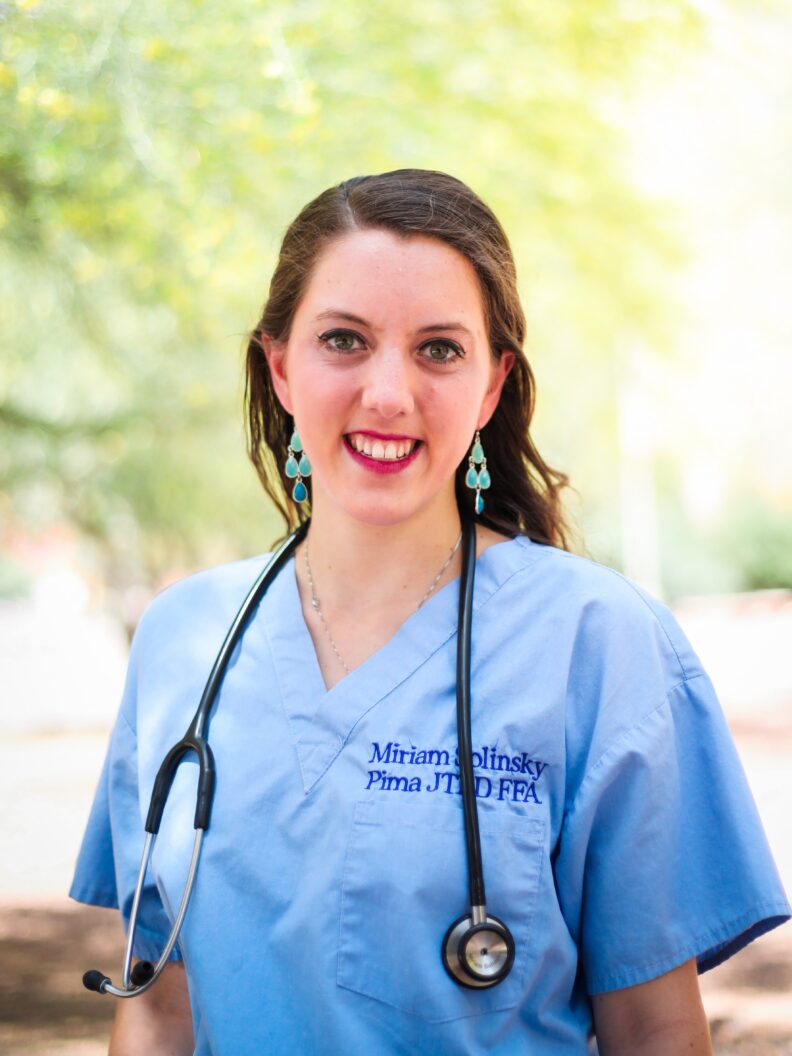 Miriam in light blue scrubs with her name embroidered on them.