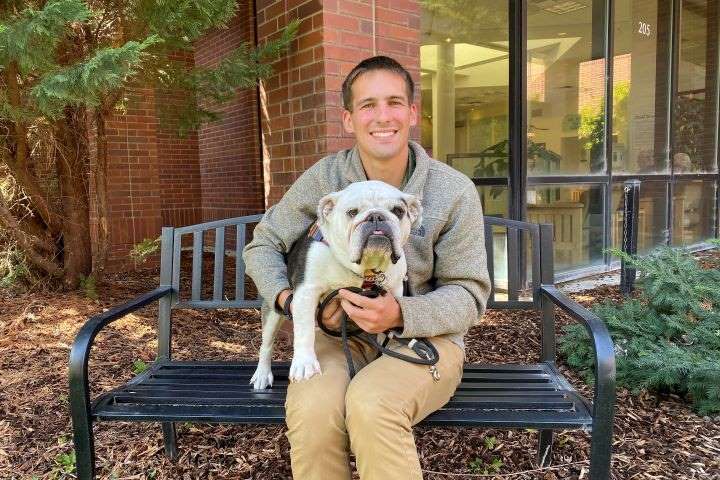 Dane sitting outside the Veterinary Teaching Hospital with Tater on his lap.