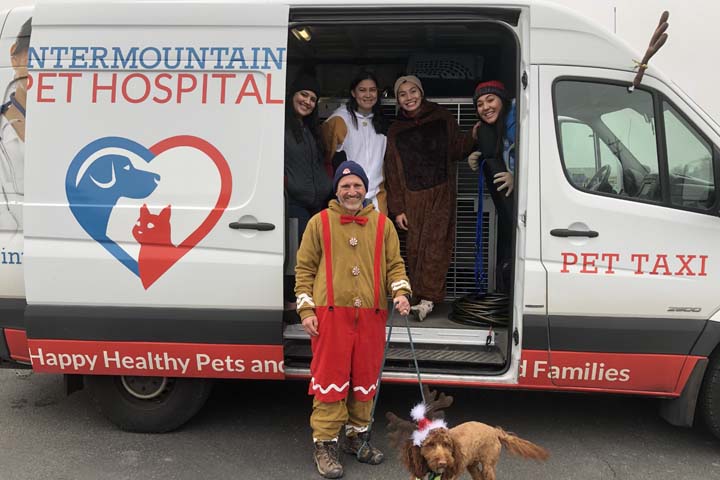 Dr. Bingham, dressed up in festive clothes standing next to a Intermountain Vet Hospital taxi.