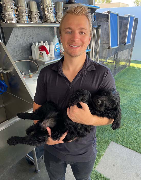 Chad holding a small black dog like you'd hold a baby.