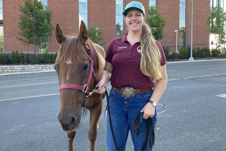 Emily with a sorrel horse near the Veterinary Teaching Hospital.
