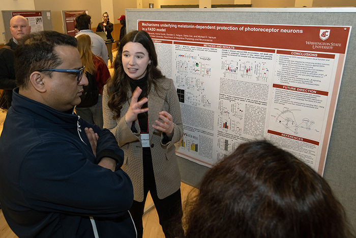 Student explaining research on their research poster to attendees of the 2023 SURCA event.