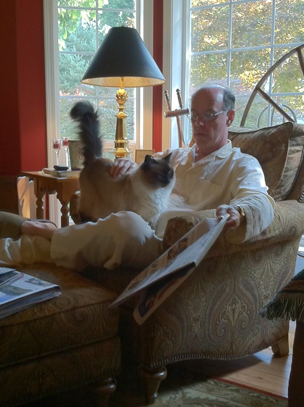 Jack and Riley in a big comfortable chair. Jack stops reading the newspaper to give Riley some attention. 