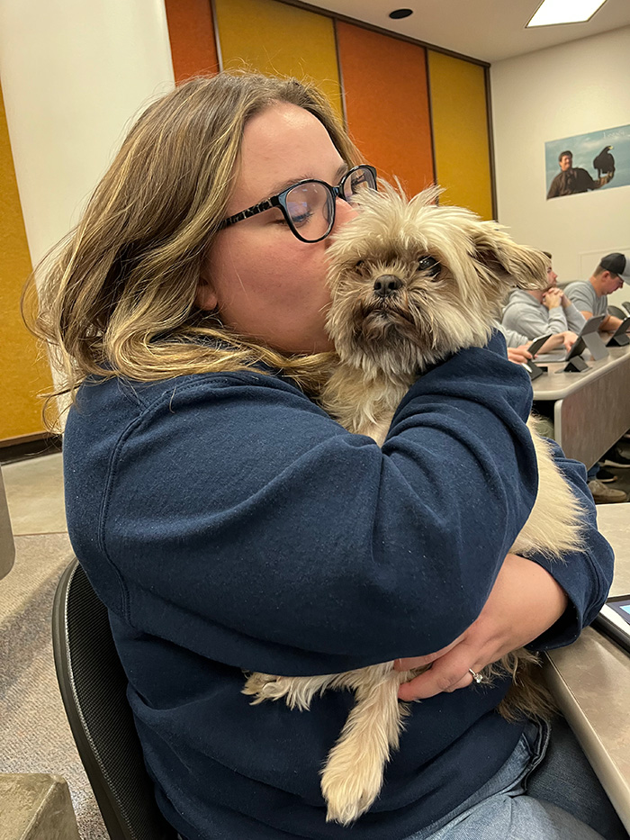 Maddie holding and kissing a small mixed breed dog.