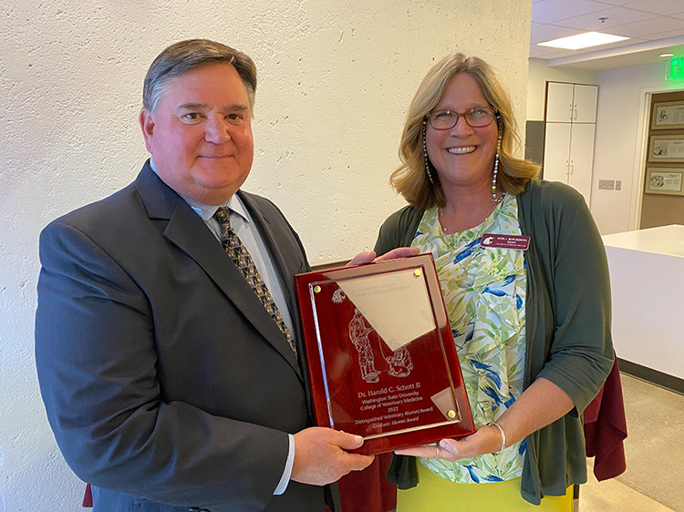 Veterinarian Dr. Harold (Hal) Schott poses with his Graduate Alumni Award while he stands alongside Dean Dr. Dori Borjesson.