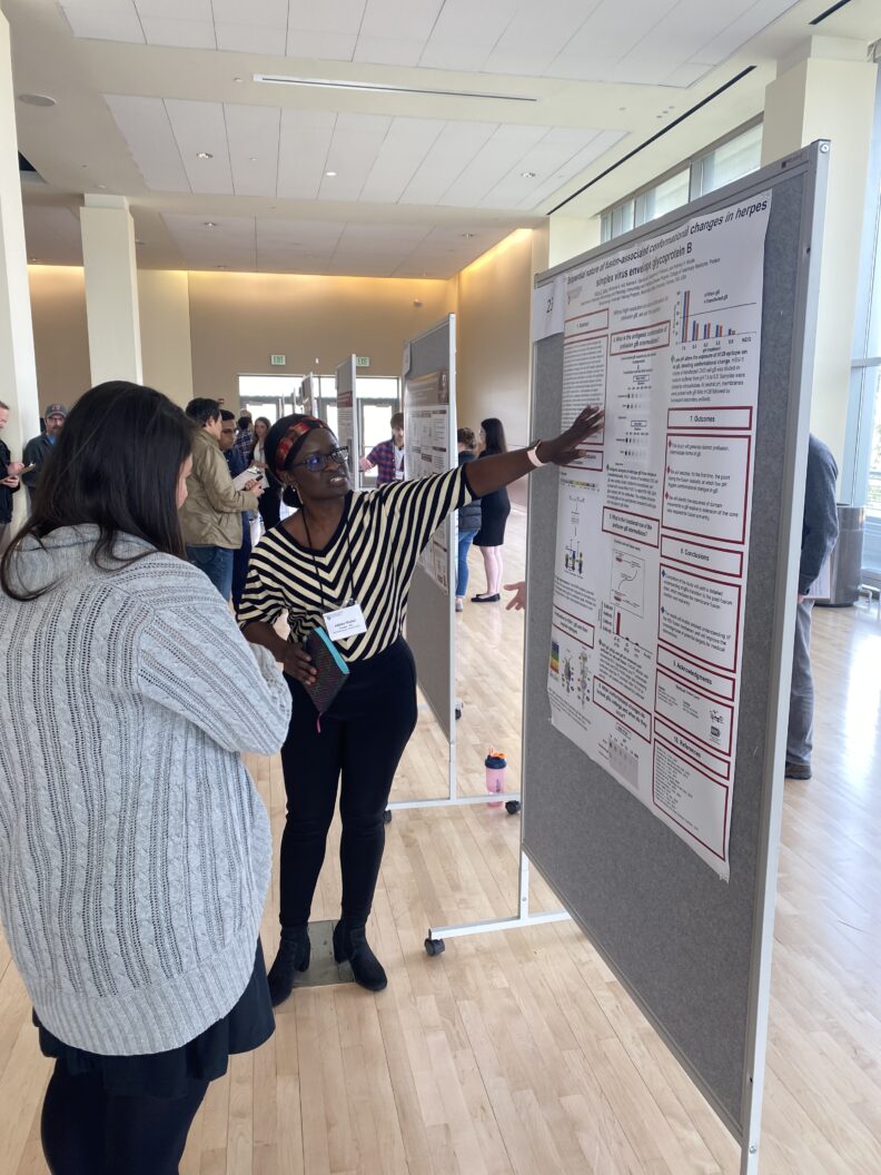 Graduate student explaining research to an observer at a research symposium.