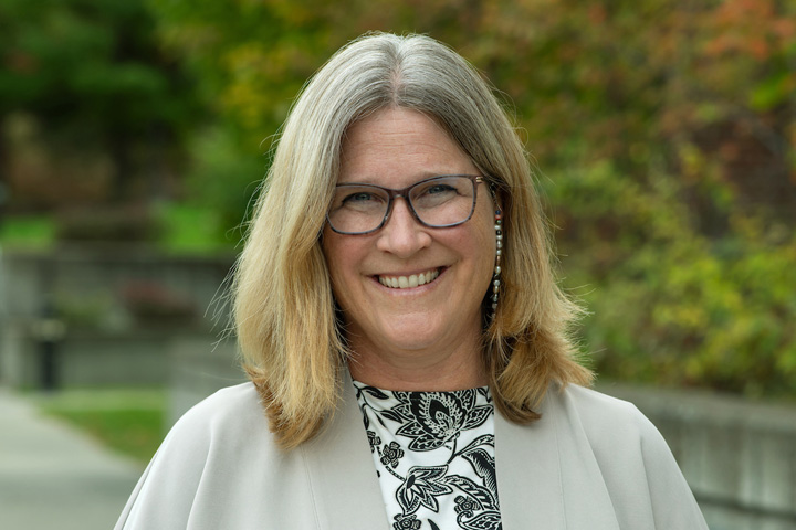 Dori outside the College in October 2023. She wears a black and white paisley top with a taupe cardigan.