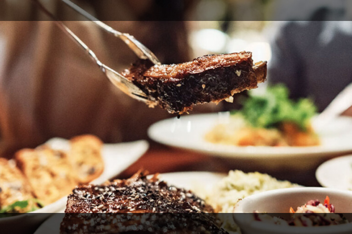 Close up photo of dinner plates including pork ribs.