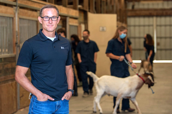 Dr. Oatley in the foreground with several workers with goats in the background.