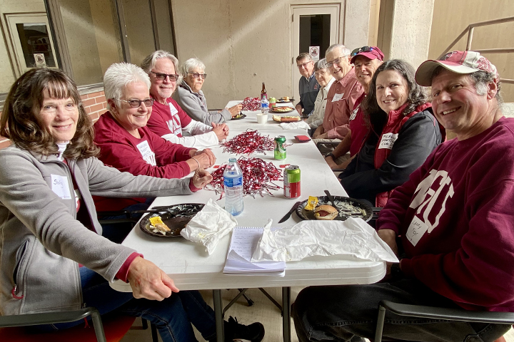 Group of alumni at a table outside Mickelsen Lounge in Bustad Hall.