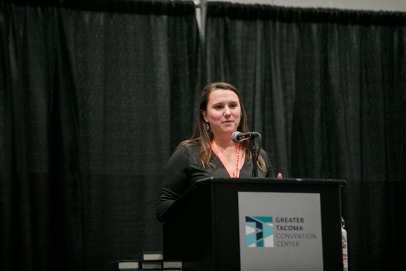 Ashley Hoyt standing at a podium and the Greater Tacoma Convention Center.