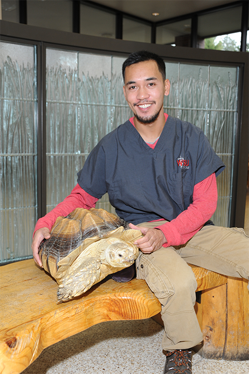 Rian Calugcugan in the teaching hospital lobby with a tortoise.