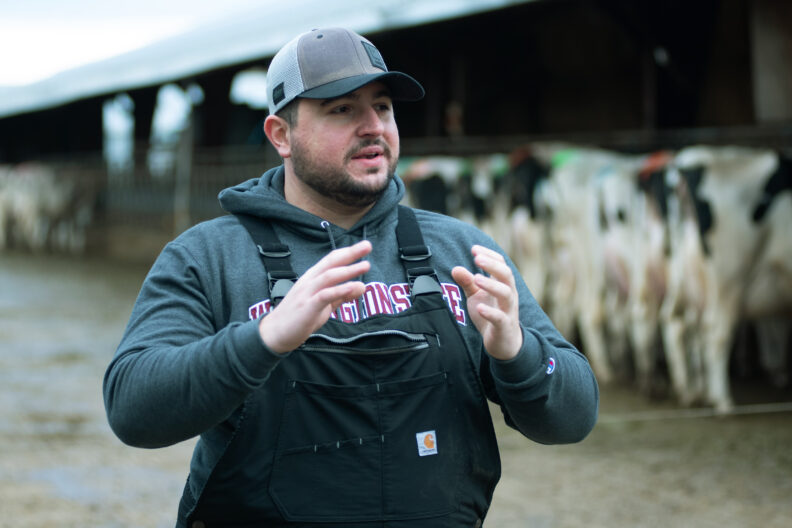 Dr. Caio Figueiredo on site with dairy cows in the background.