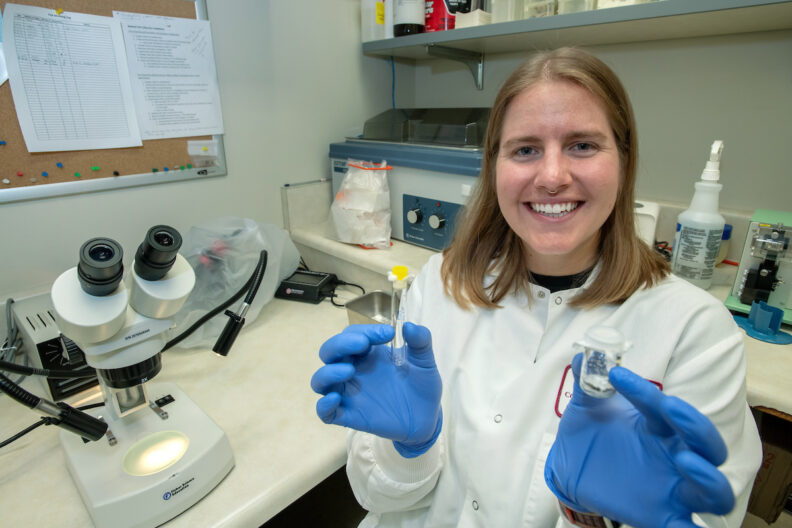 Cameron Coyle holds vials of ticks in a lab.