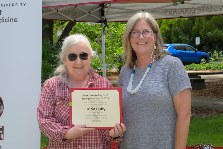Tricia holding her certificate as she is standing with Dean Dori.