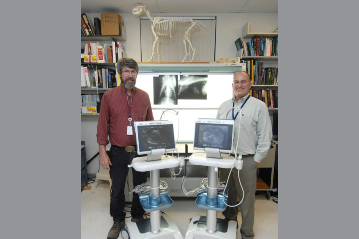 (l-r) Drs. Roberts and Mattoon standing next to two portable ultrasound machines.