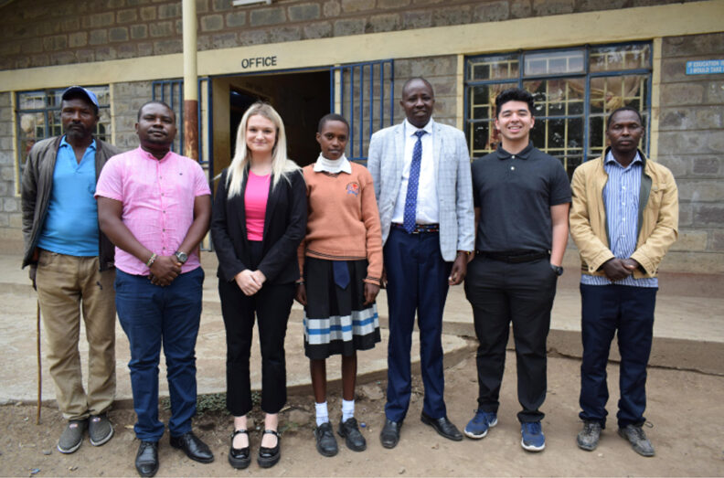 Group standing in front of a cinder block building.
