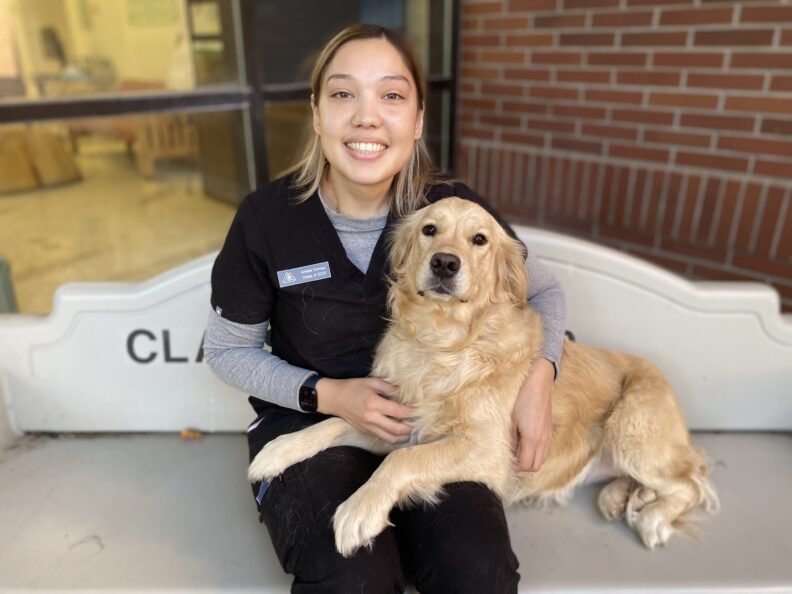 Arielle Gomez-Ramirez sits with her golden retriever outside of the VTH.