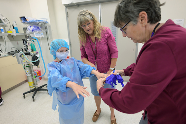 Maddie Hedrick is helped into surgical scrubs.