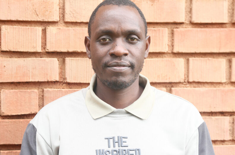 Dr. Ngetich standing against a brick wall.