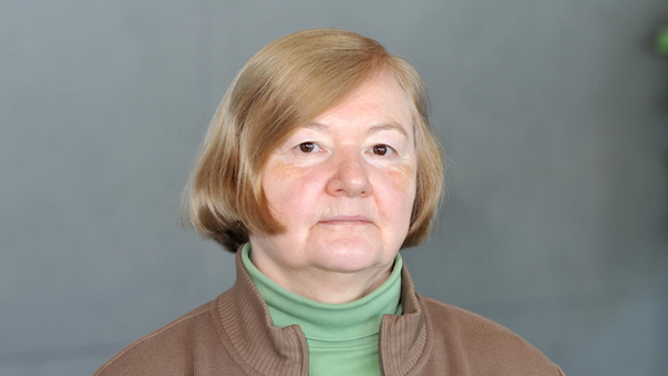 Marina outside with a grey wall behind her.