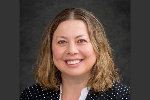 Professional headshot of Ekaterina. She is wearing a navy blue jacket with small white polka dots.