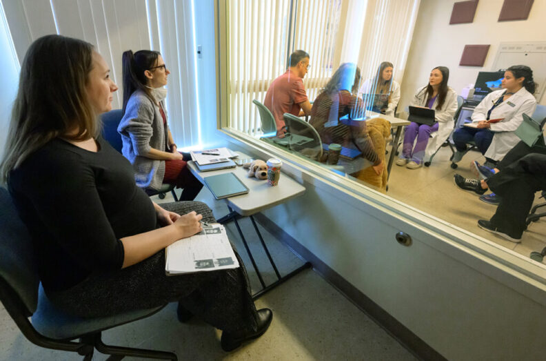 Sarah Calvin, left, and Stephanie Byrne, second from left, veterinarians who graduated from WSU’s College of Veterinary Medicine, observe current DVM students through a one-way mirror.
