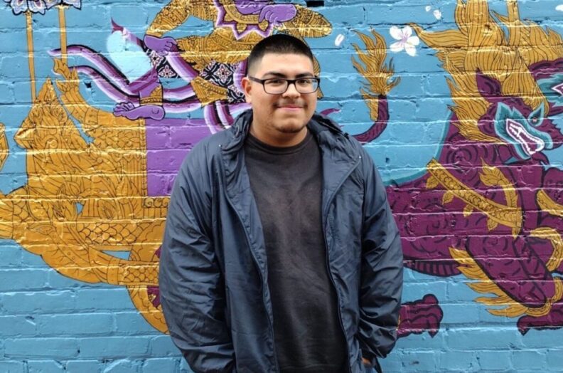 Isaiah Rodriguez-Jimenez poses in front of a mural.