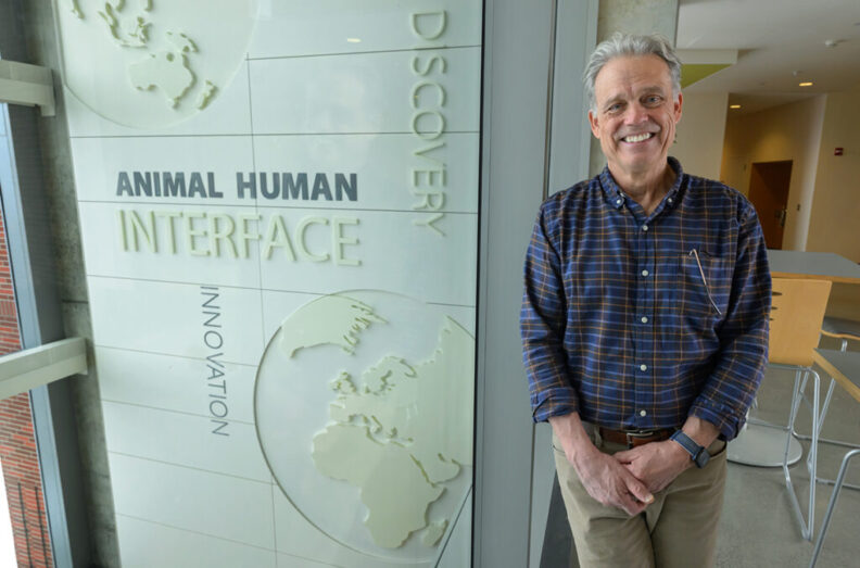 Tom standing next to signage inside the Allen School.