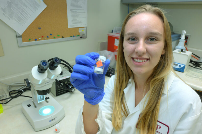 Kaylee Vosbigian holds a vial of ticks.