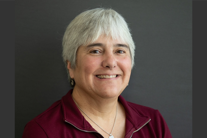 Professional headshot of Gina Meyer in photo studio. She is wearing a dark cranberry colored top.