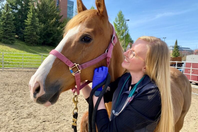 Elizabeth Evans stands next to a horse.