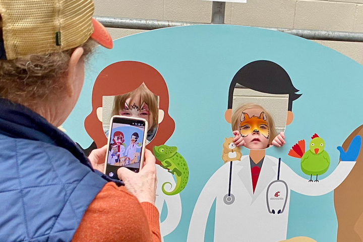 Parent, getting photo of kids in photobooth. You can see the photo in the photo.