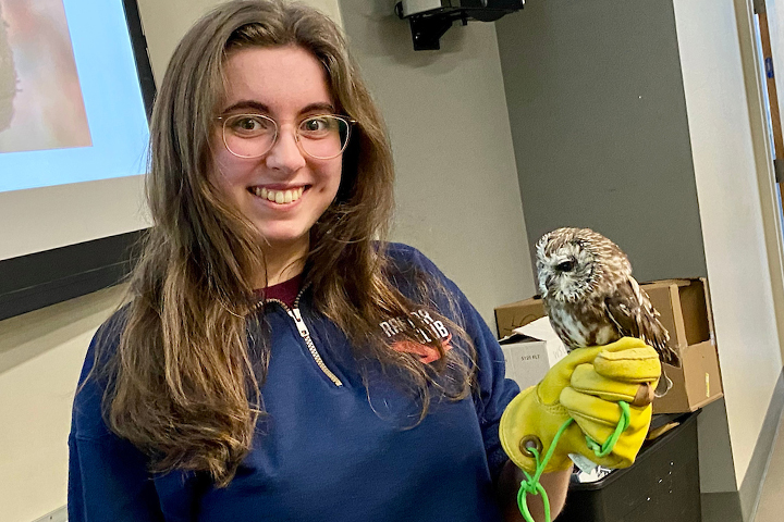 A raptor club member holding a tiny owl.