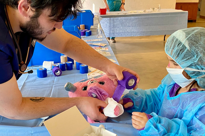 Young girl getting assitance with "surgery" on her stuffed animal.