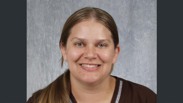 Alexis in a photo studio, with a grey textured background behind her.