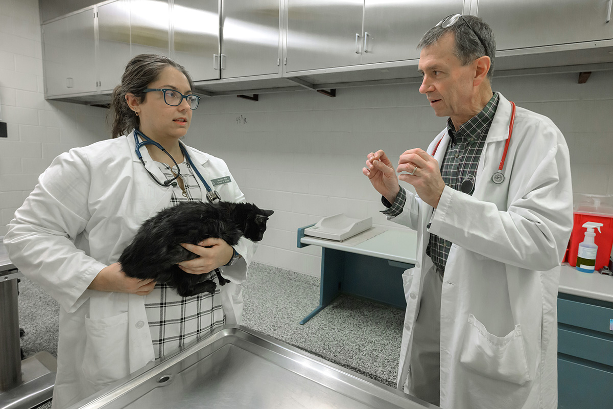 Rance Sellon talks with student holding a cat