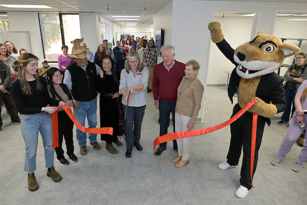Group of people cutting a ribbon.