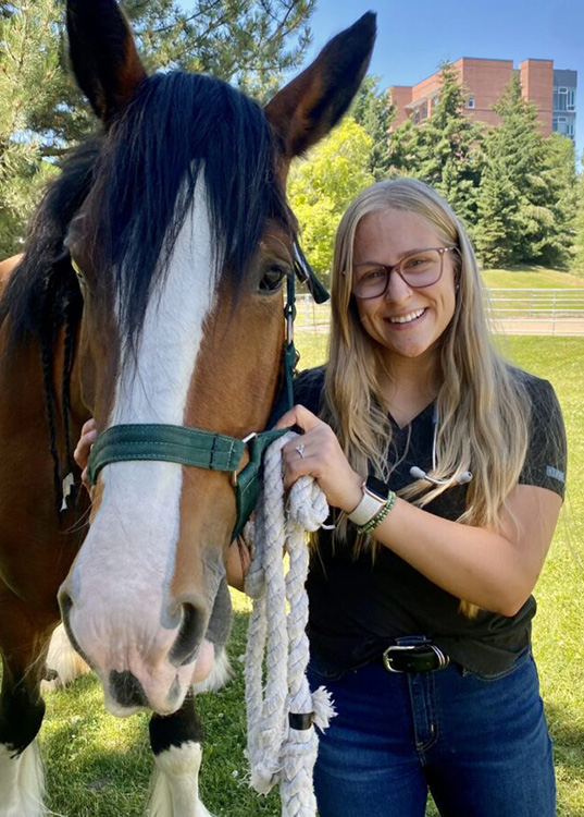 Emma Impala poses with a horse.