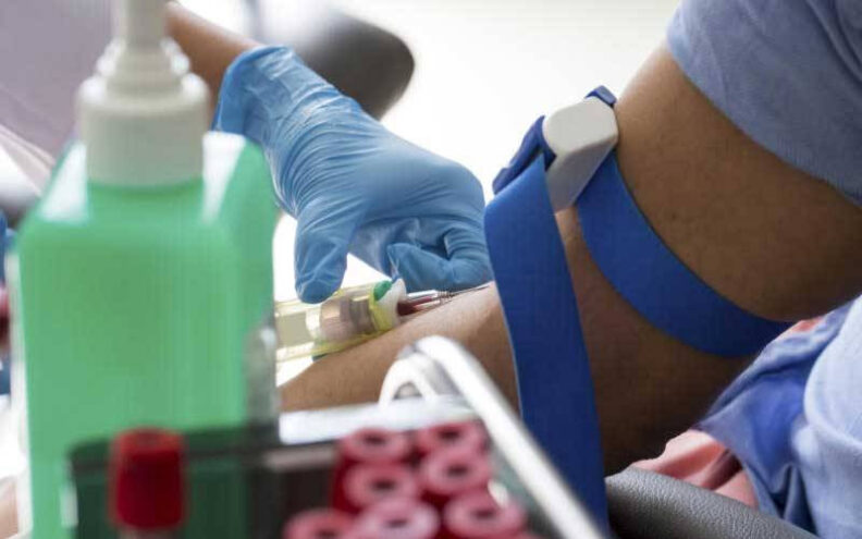 Close up image of a patient's arm while a nurse is taking a blood sample for testing.