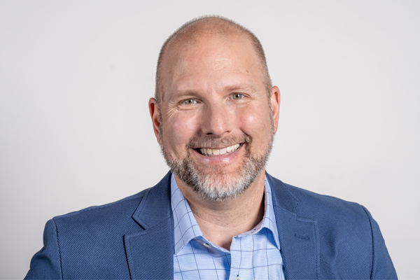 Headshot of Jason. He's wearing a blue jacket and light blue dress shirt.