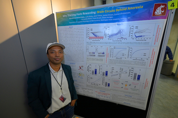 Student in front of poster at research symposium.